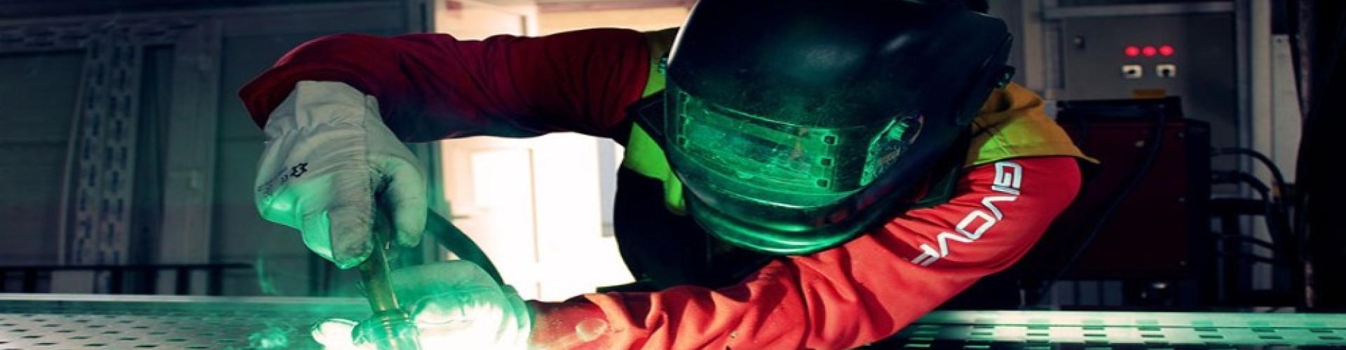 A welder working on metal fabrication in a manufacturing facility.